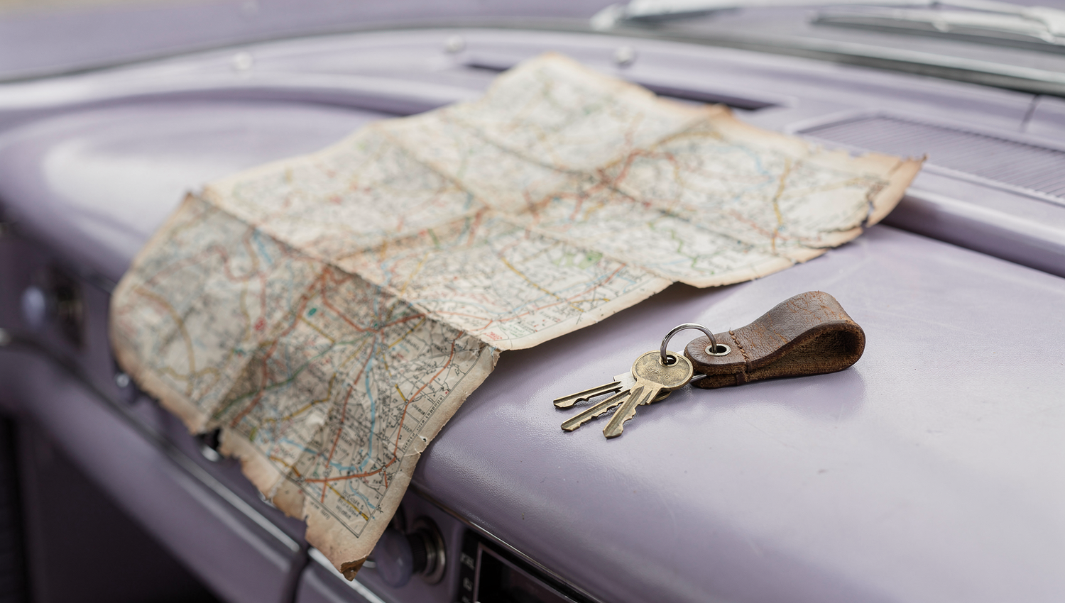 Old map and keys on a classic car hood